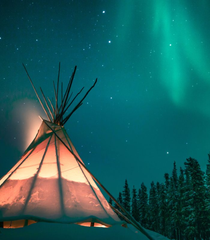 Glowing tipi / teepee in the snowy forest under the northern lig Glowing tipi / teepee in the snowy forest under the northern lig